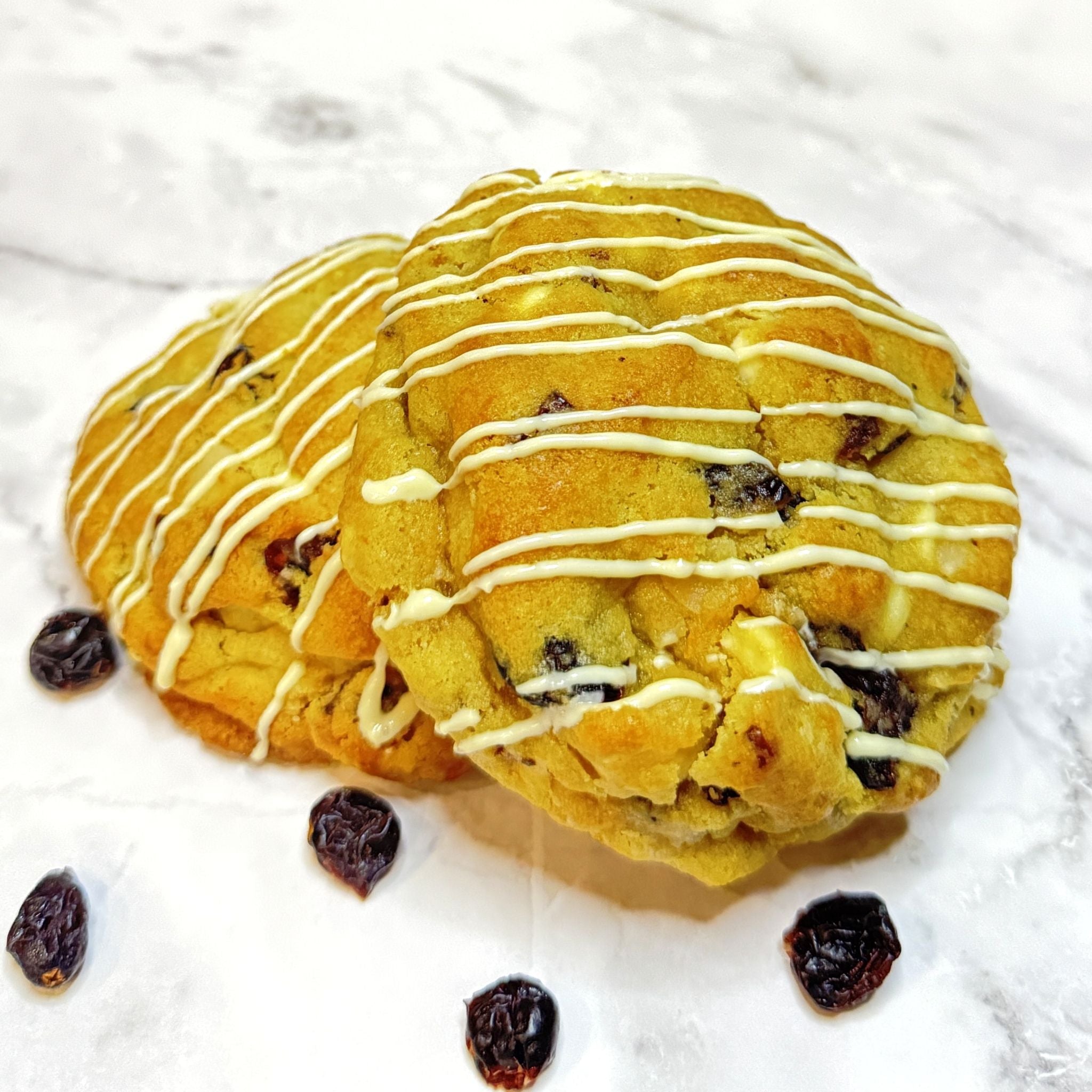 Two Scarlet Zest cookies from Le Petit Cookie stacked on top of each other on a marble countertop.