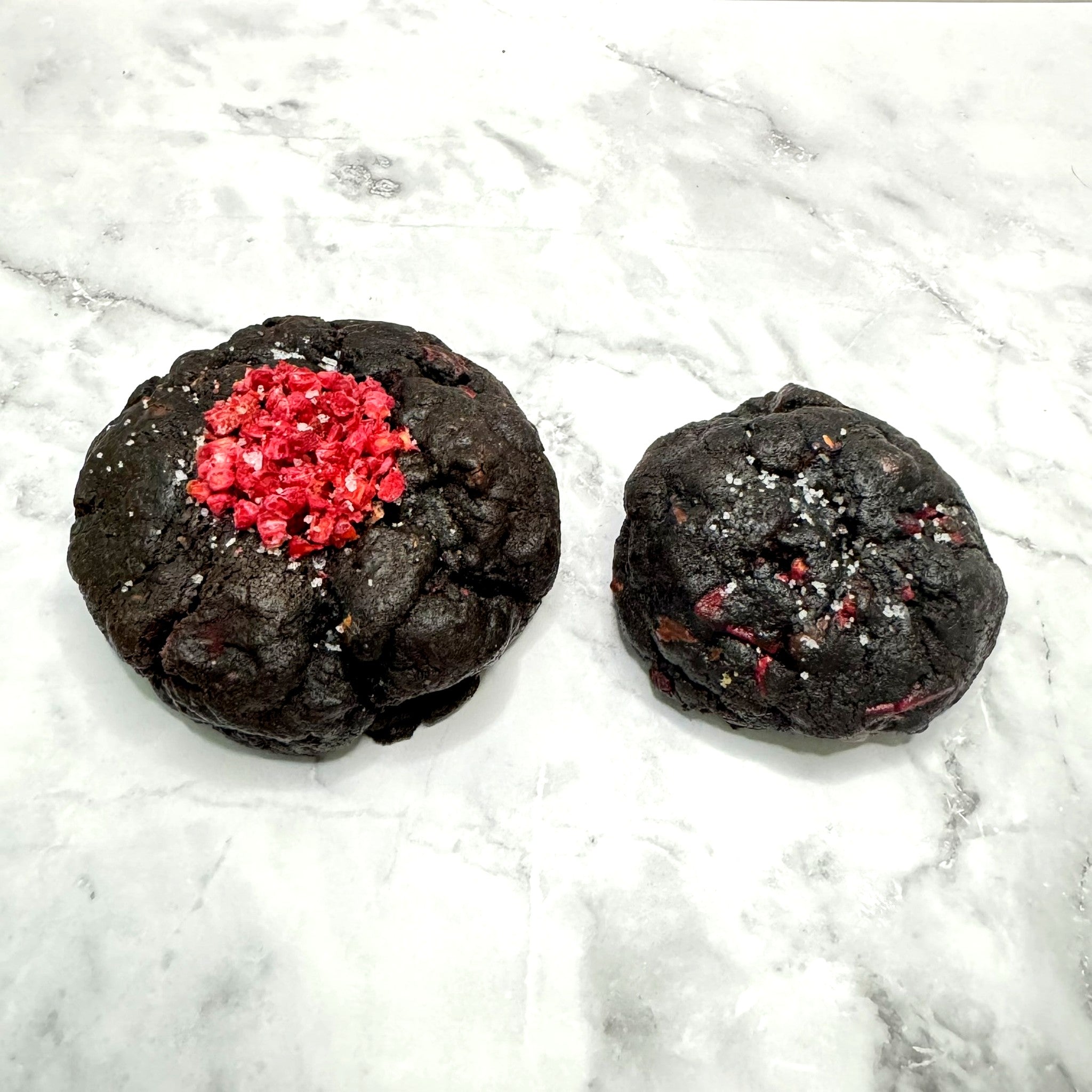 Midnight Berry Cookies: petit (3oz) next to regular (5.3oz) for size comparison on a marble countertop.