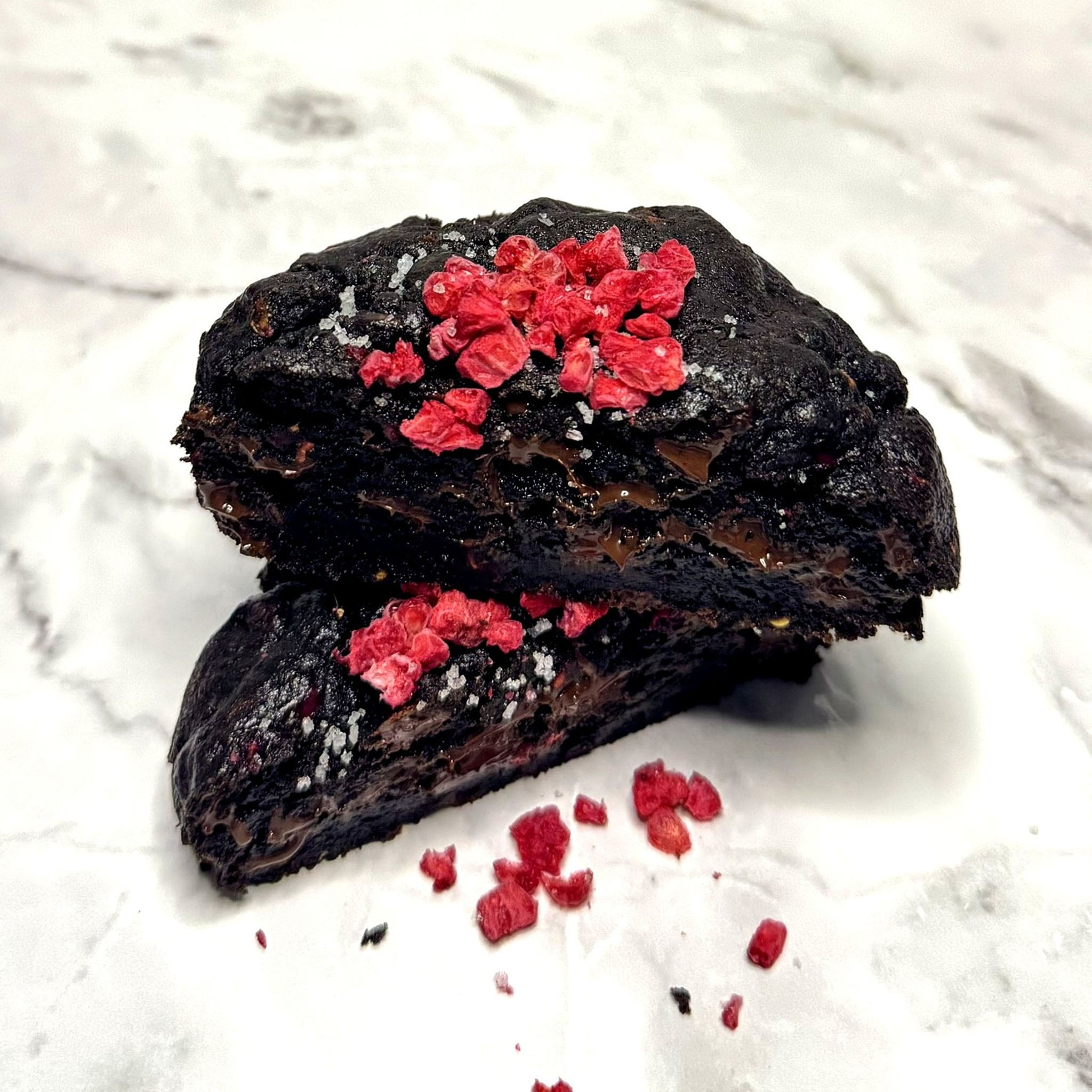 Midnight Berry Cookie cut in half, showcasing gooey and rich dark chocolate.
