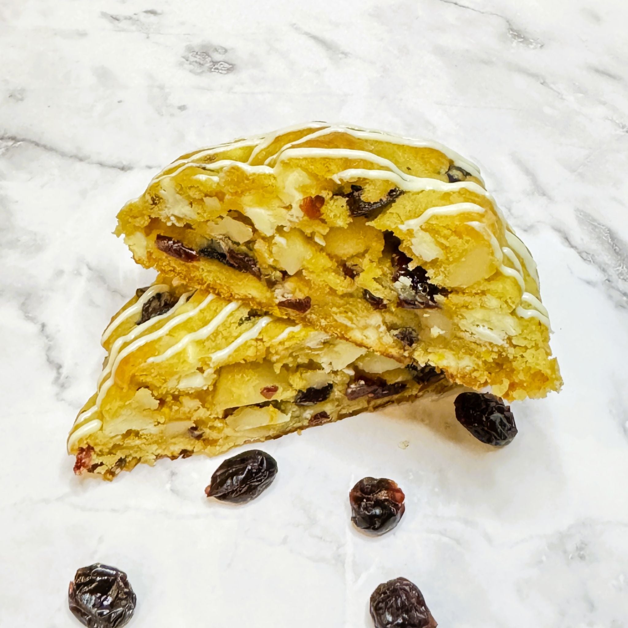 Scarlet Zest Cookie cut in half, showcasing the buttery cookie with macadamia nuts, creamy white chocolate and sweet cranberries.