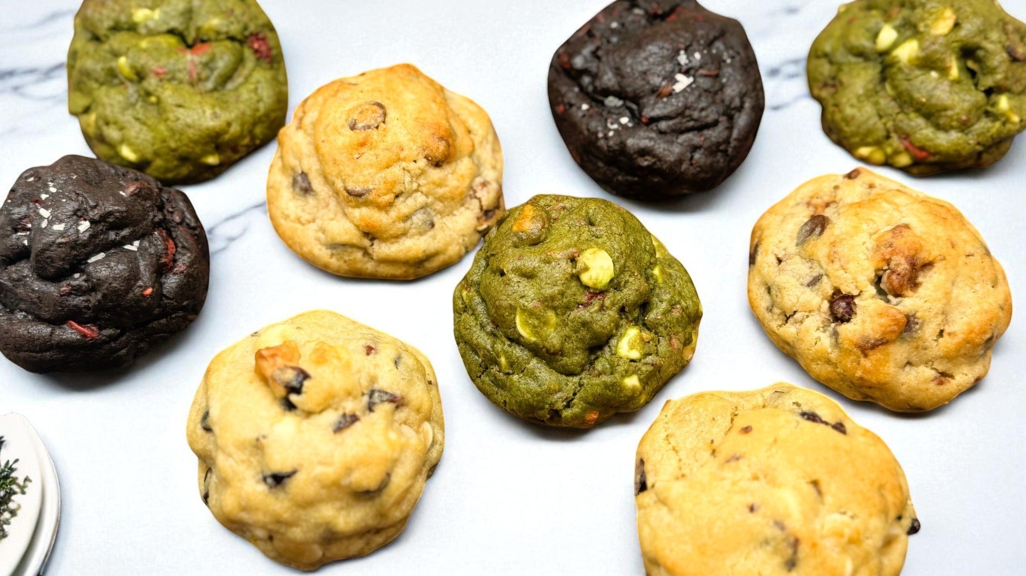 Wide banner showing an assortment of Le Petit Cookies gourmet selectoins on a marble countertop.