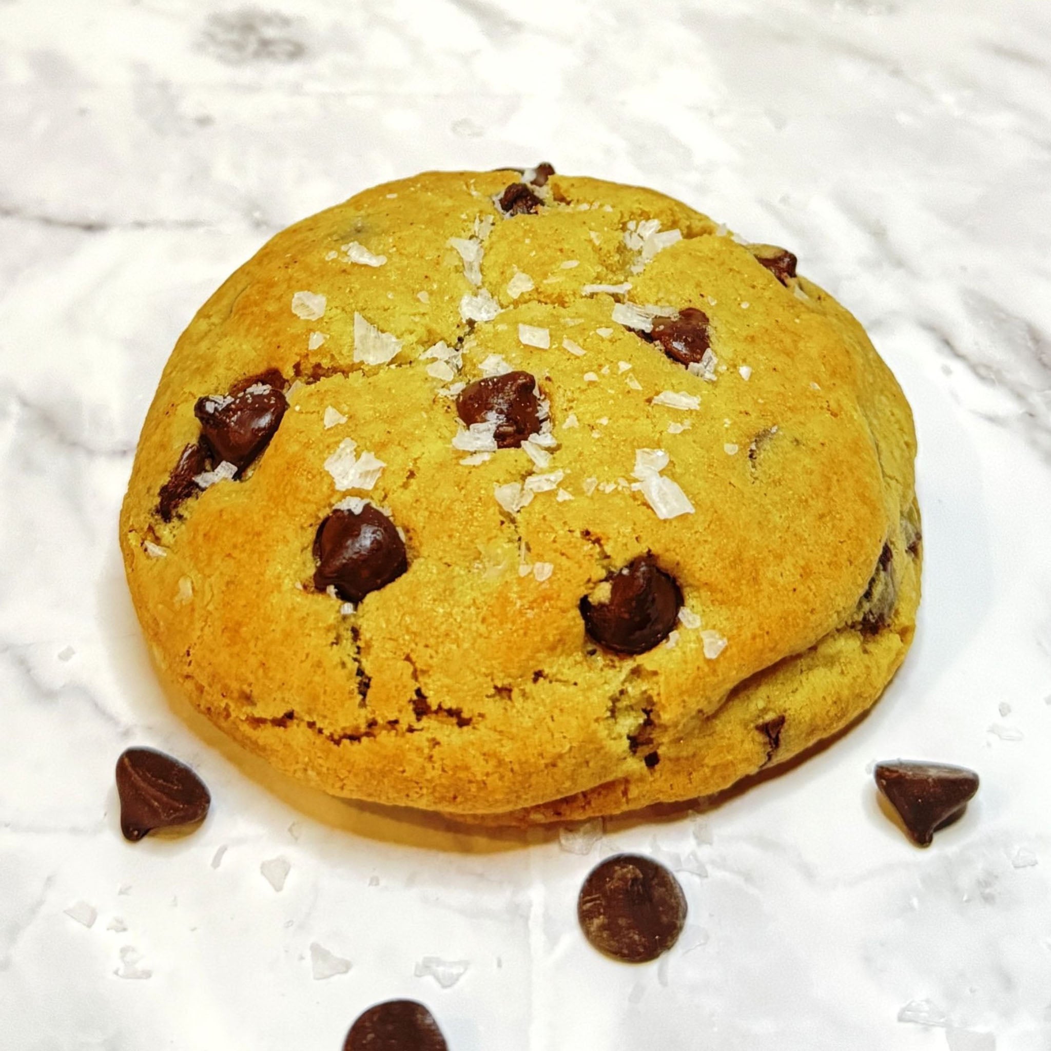 Front view of a Golden Crumb Cookie from Le Petit Cookie. A sophisticated take on a classic chocolate chip cookie with rich brown butter, melty chocolate, and finished with flaky sea salt.