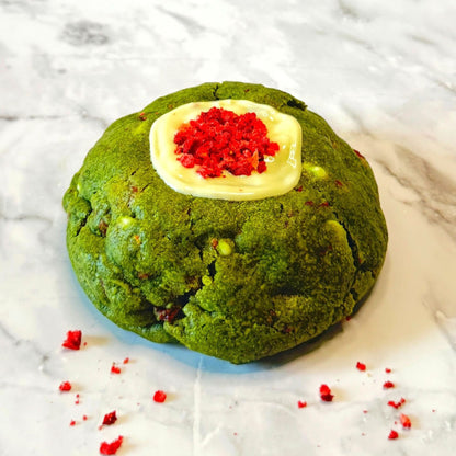 Front view of the Jade Kiss Cookie with matcha, Valrhona® Strawberry chips and creamy white chocolate on a marble countertop.