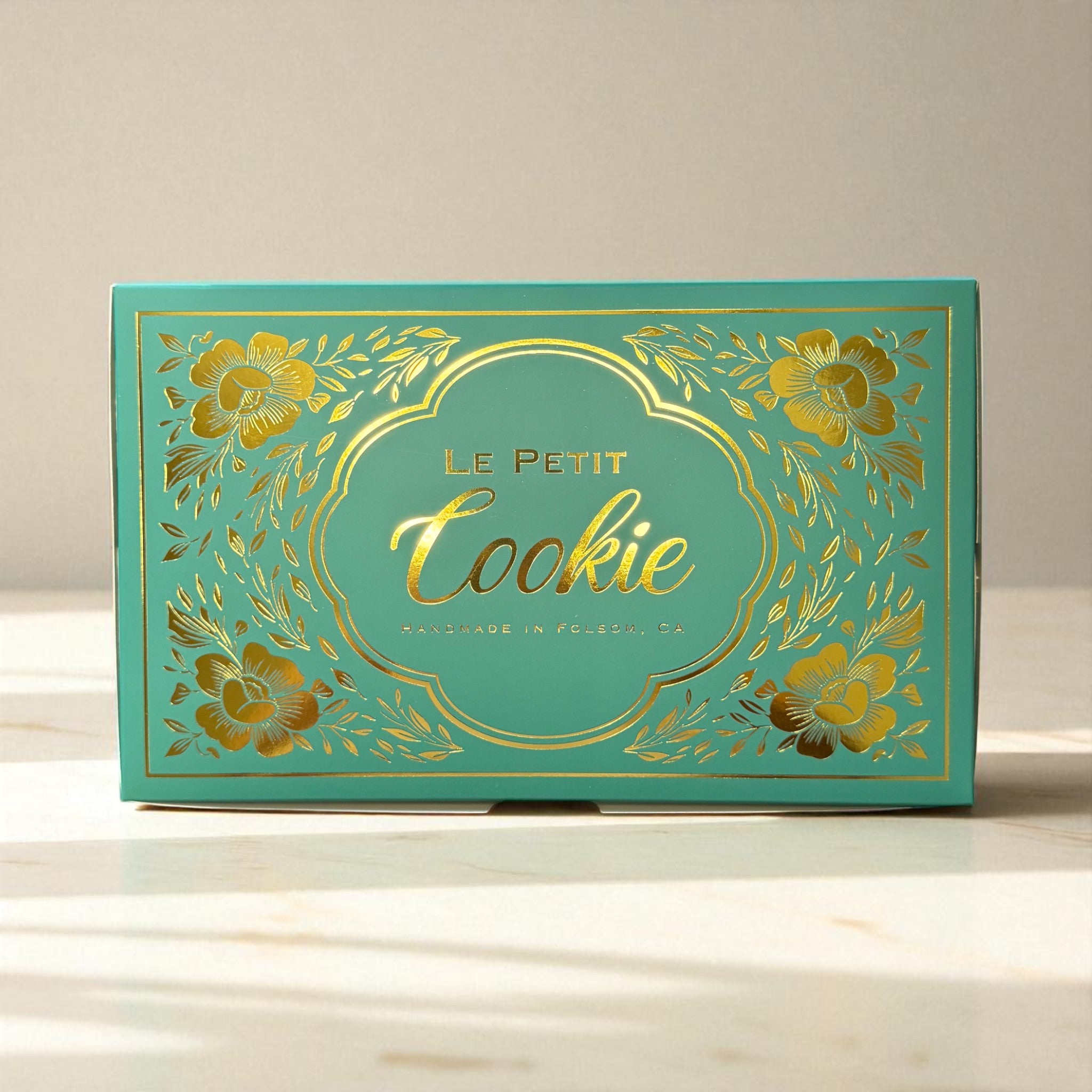Petit assortment cookie box from Le Petit Cookie featuring a teal box with gold writing that reads "Le Petit Cookie Handmade in Folsom, CA"