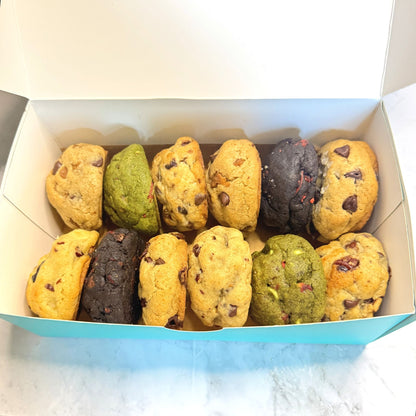 A top down view of an open petit assortment box from Le Petit Cookie showcasing a variety of 12 different gourmet petit cookies.