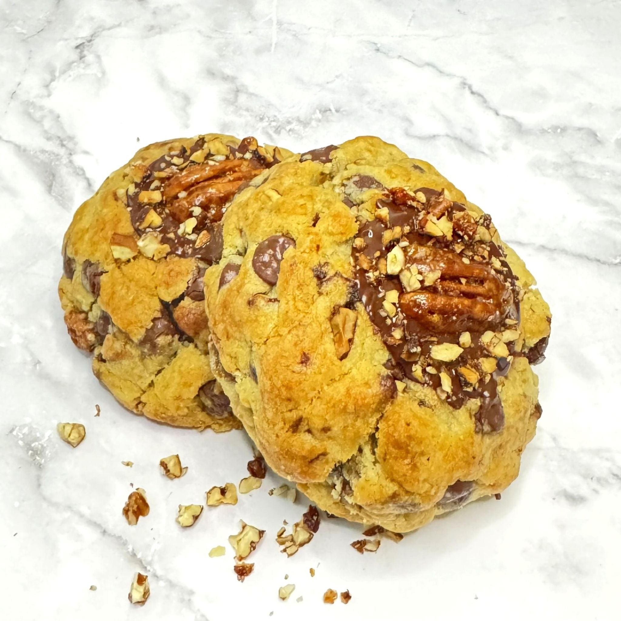 Two Golden Banane cookies from Le Petit Cookie stacked on top of each other on a marble countertop.