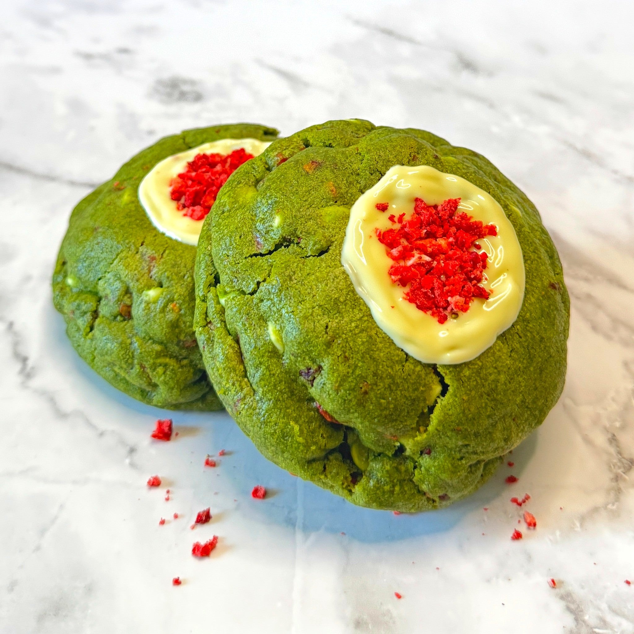 Two Jade Kiss cookies from Le Petit Cookie stacked on top of each other on a marble countertop.