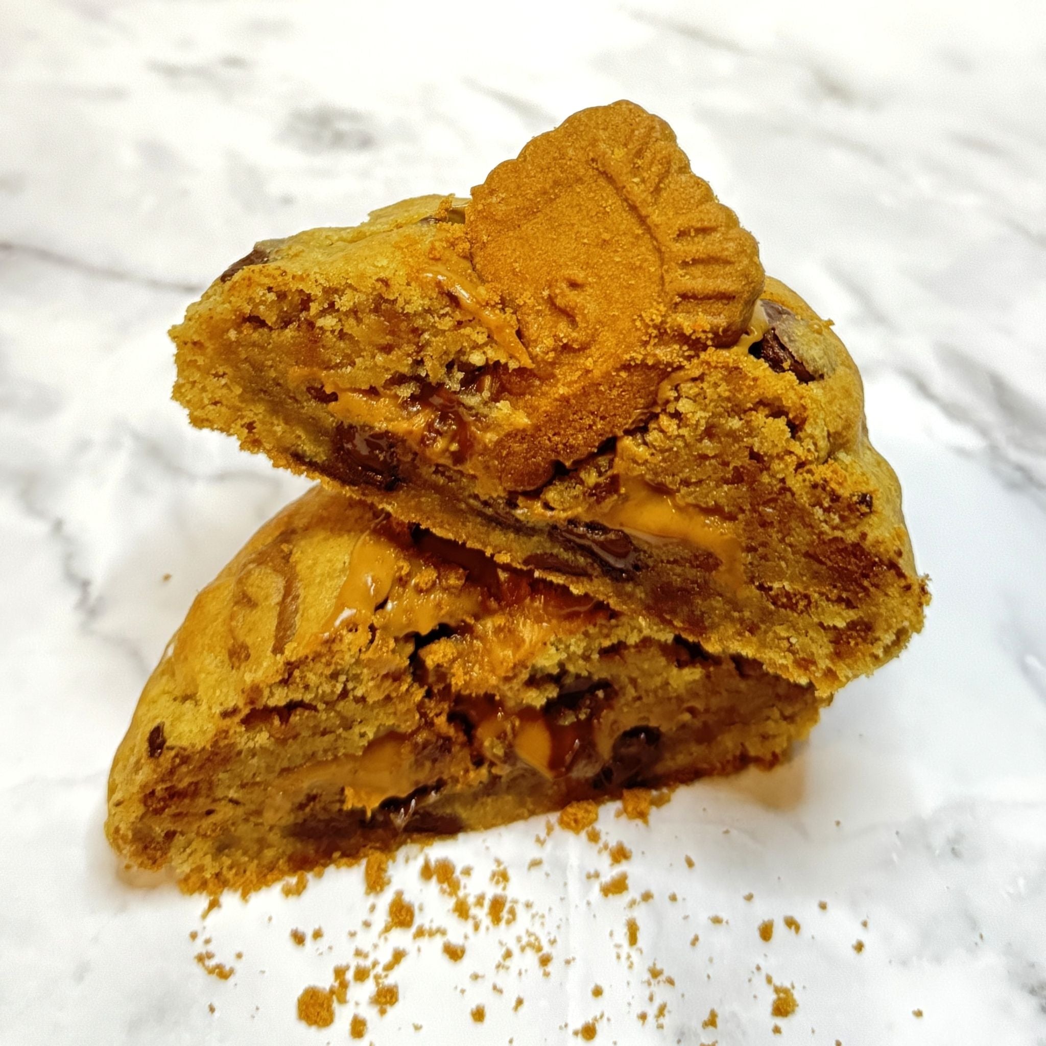 Amber Dusk Cookie cut in half, showcasing the velvety cookie butter filling, semi-sweet chocolate chips and Biscoff cookie.