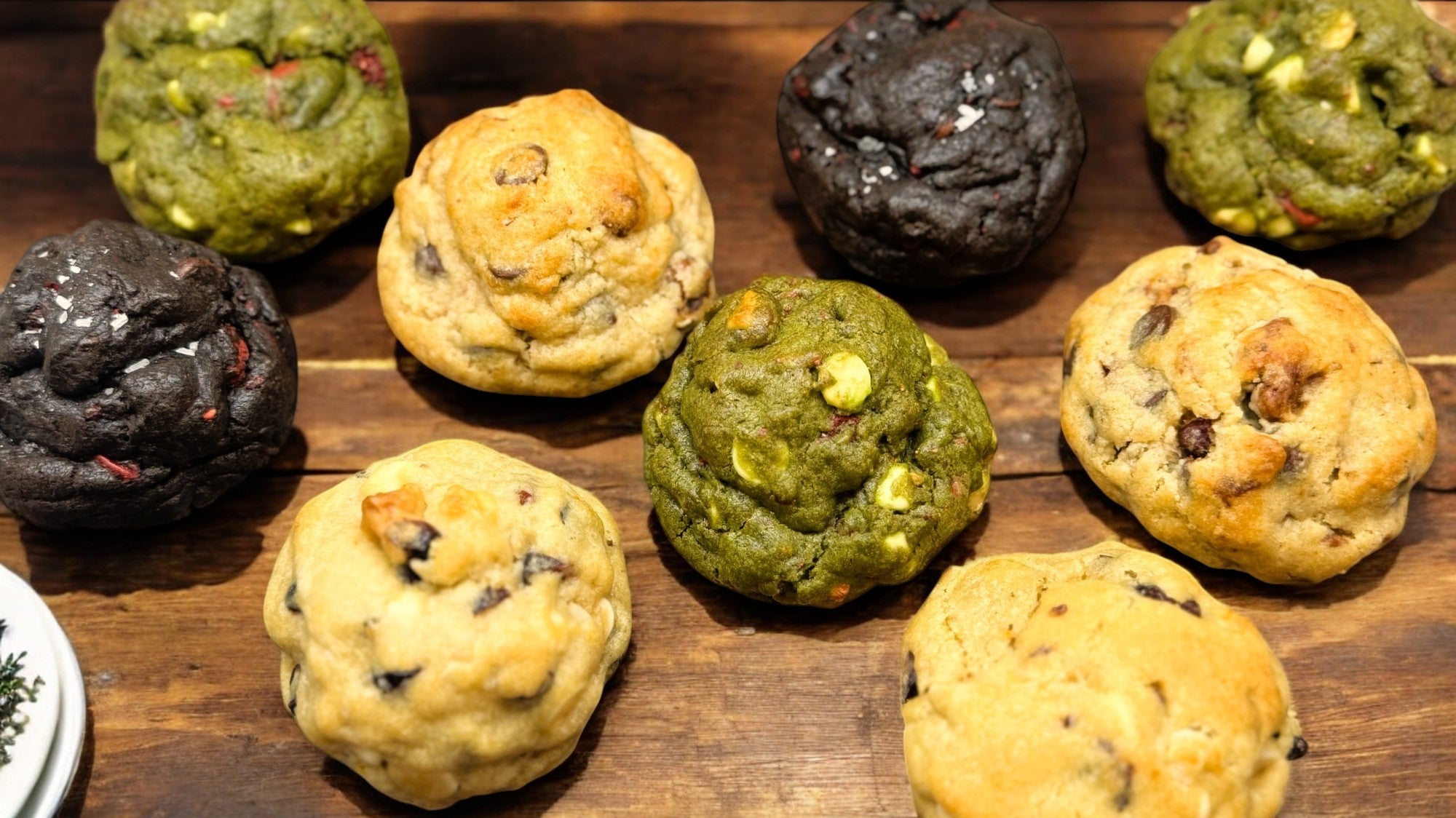 Assortment of gourmet cookies from Le Petit Cookies displayed on a dark wooden tabletop.